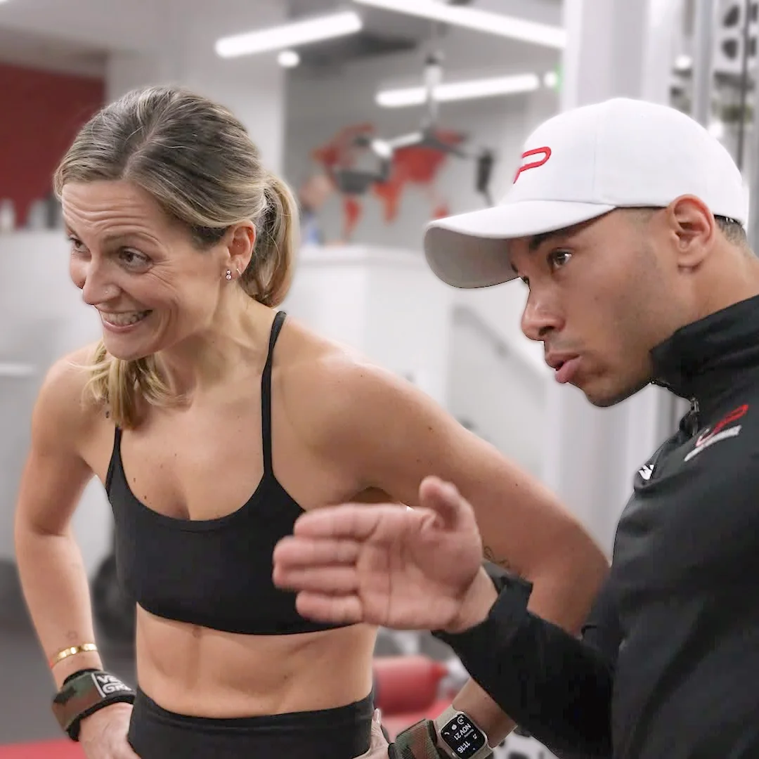 Female athlete listening attentively to a male coach giving instructions in a gym.