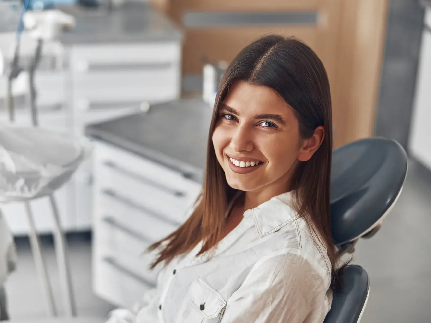 Smiling young woman sitting in a dental chair in a modern dental office.