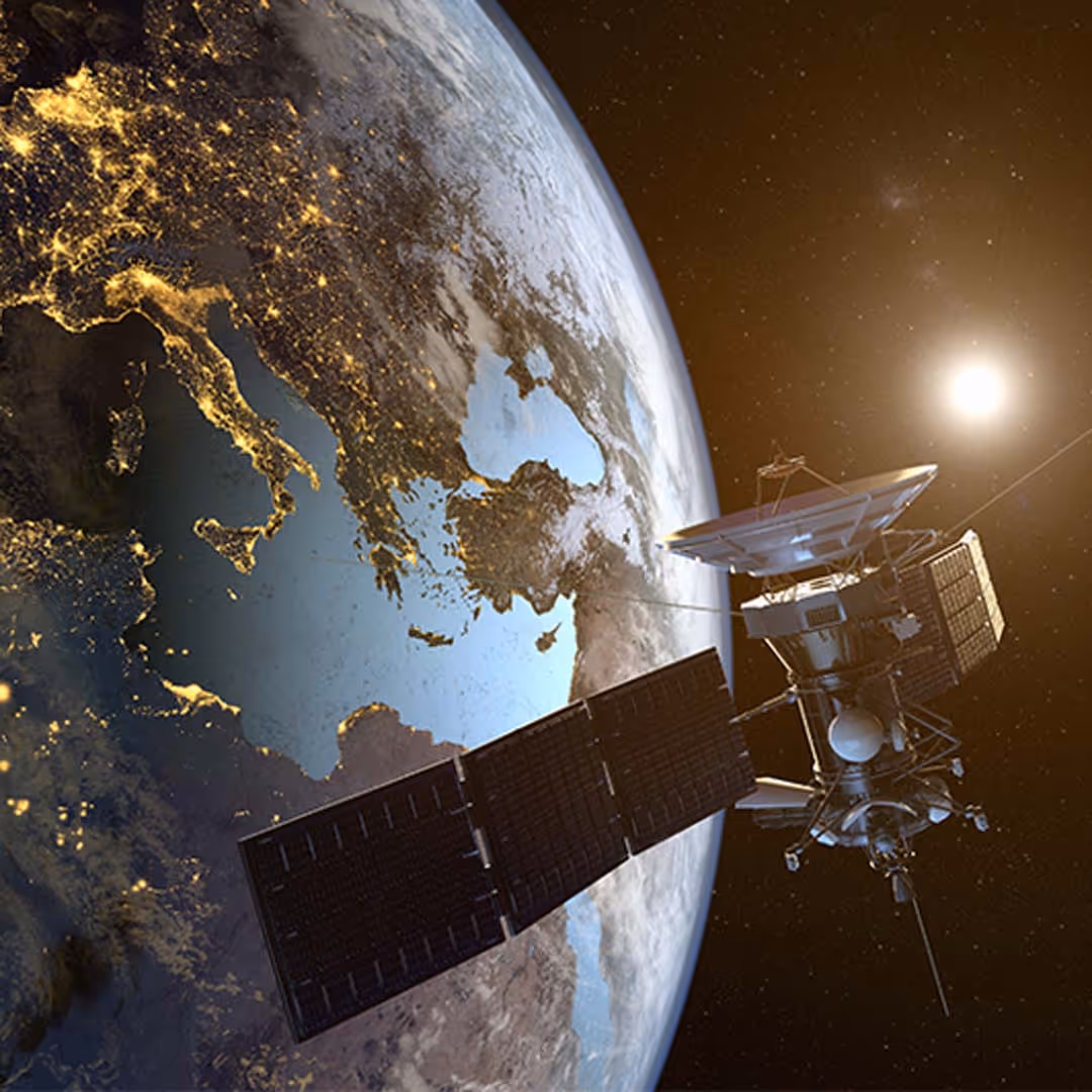 Satellite orbiting Earth with illuminated city lights over Europe and the sun shining in the background.