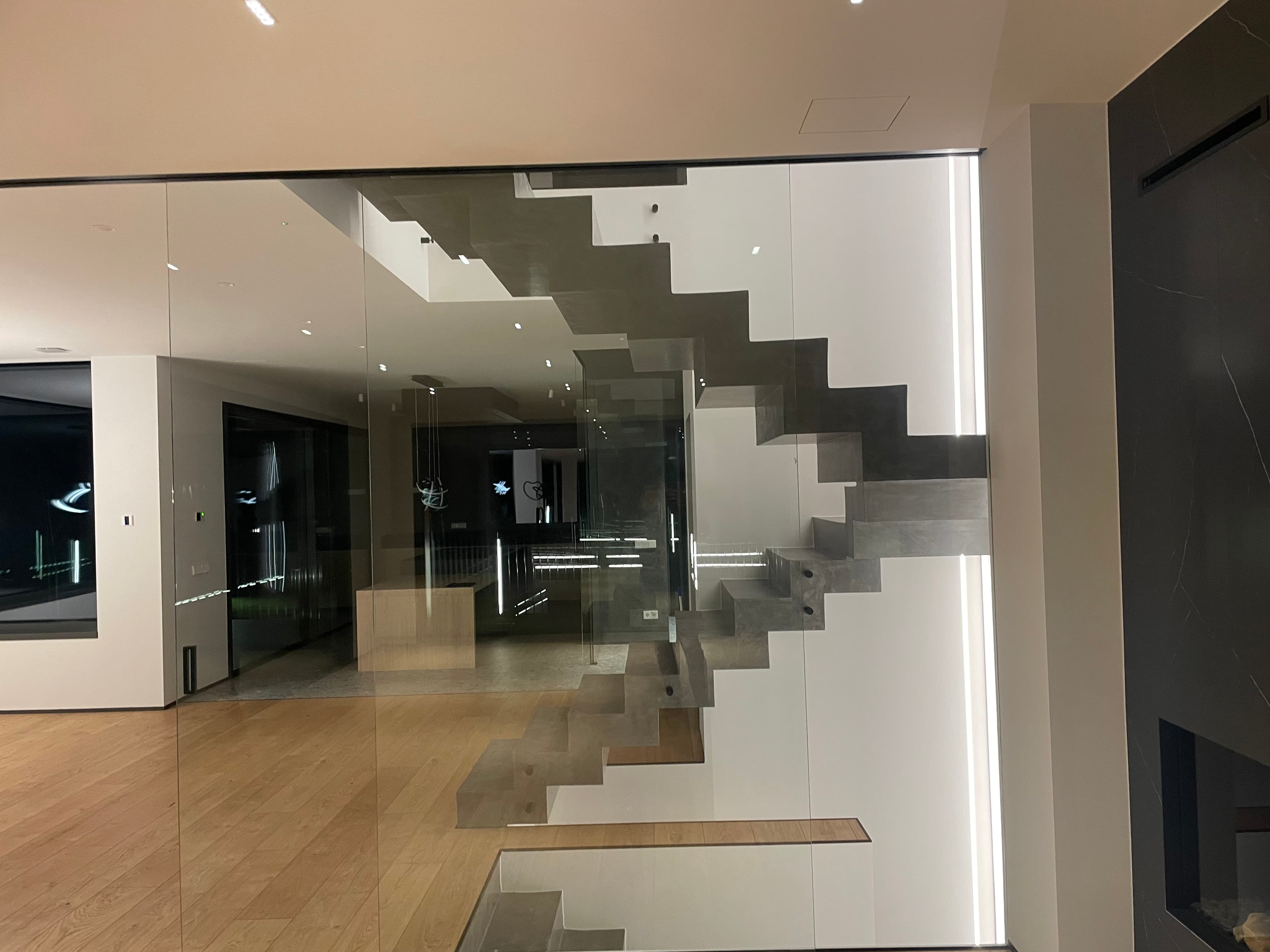 Escala de disseny modern suspendida amb vidre transparent al voltant en un interior d'estil minimalista amb terres de fusta clara.