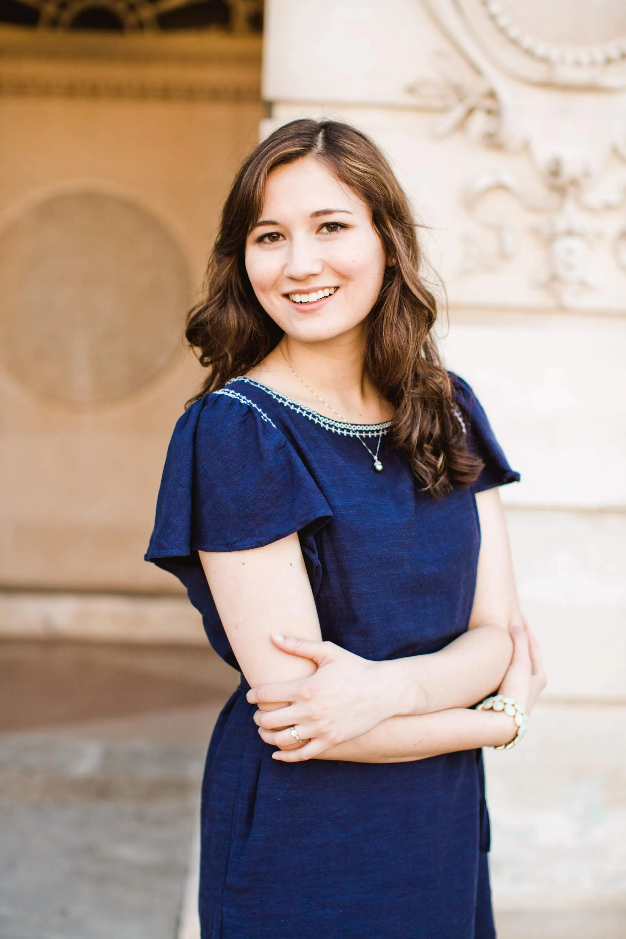 Woman in blue dress smiling confidently against architectural background