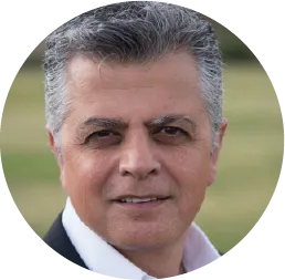 Headshot of a middle-aged man with gray hair smiling warmly outdoors