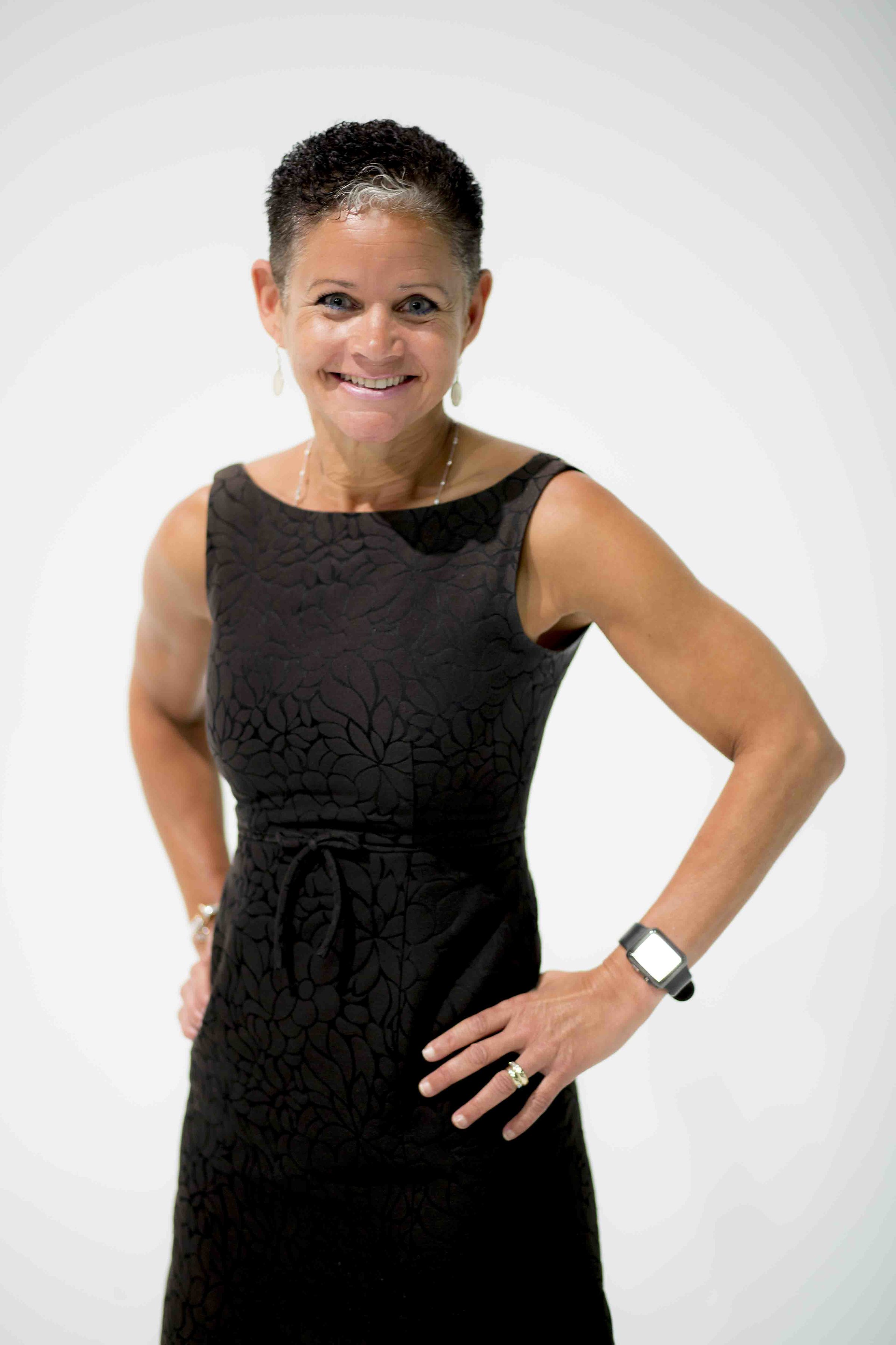 Smiling woman in black textured dress posing confidently against white background