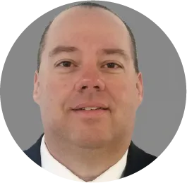 Professional headshot of a middle-aged man smiling in business attire