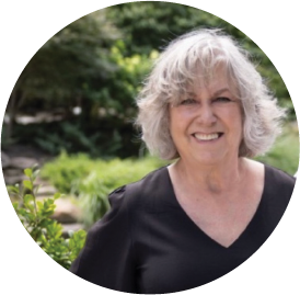Smiling senior woman with curly gray hair standing in garden