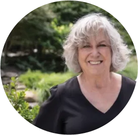 Smiling senior woman with curly gray hair standing in garden