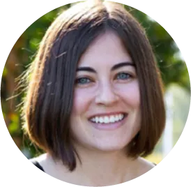 Smiling person with short dark hair in front of blurred green background