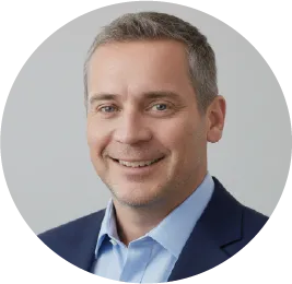 Professional headshot of a smiling man in a blue suit and shirt