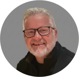 Smiling older man with glasses and gray beard wearing black sweater