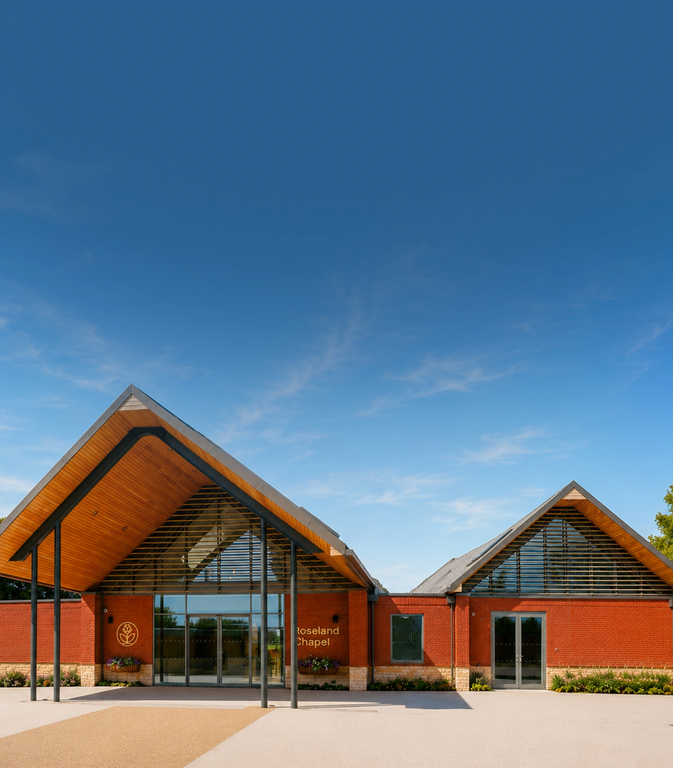 Brick building with two peaked roofs labeled Roseland Chapel under clear blue sky.