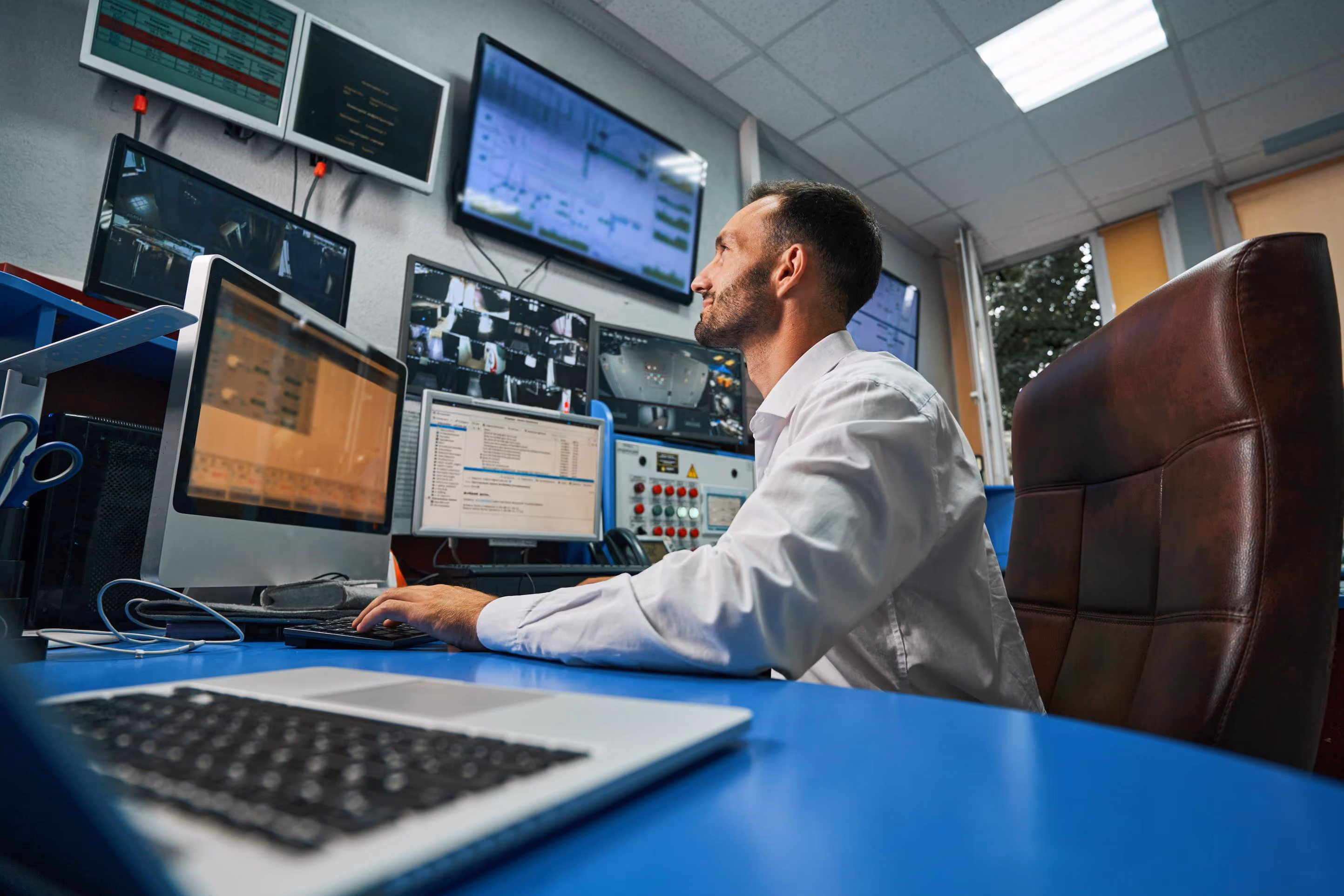 Man with beard holding clipboard and pen, inspecting servers in a dark data center room.