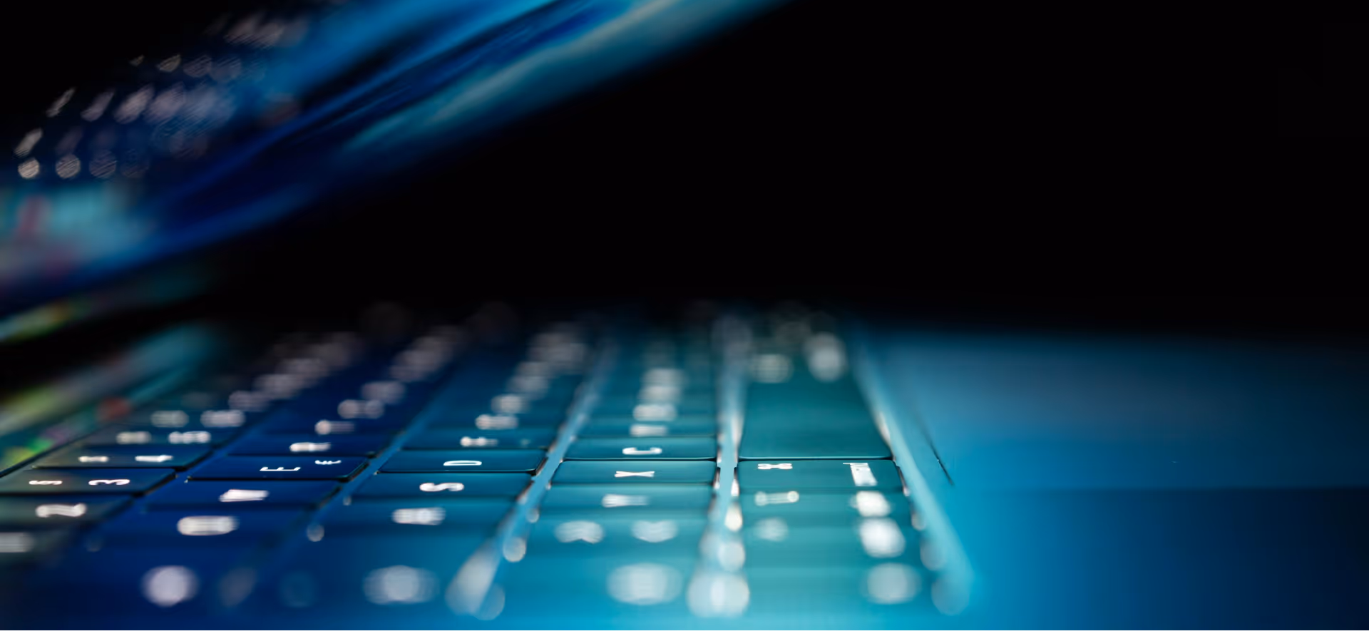 Grayscale close-up of a backlit keyboard with a text overlay about physical and cybersecurity.