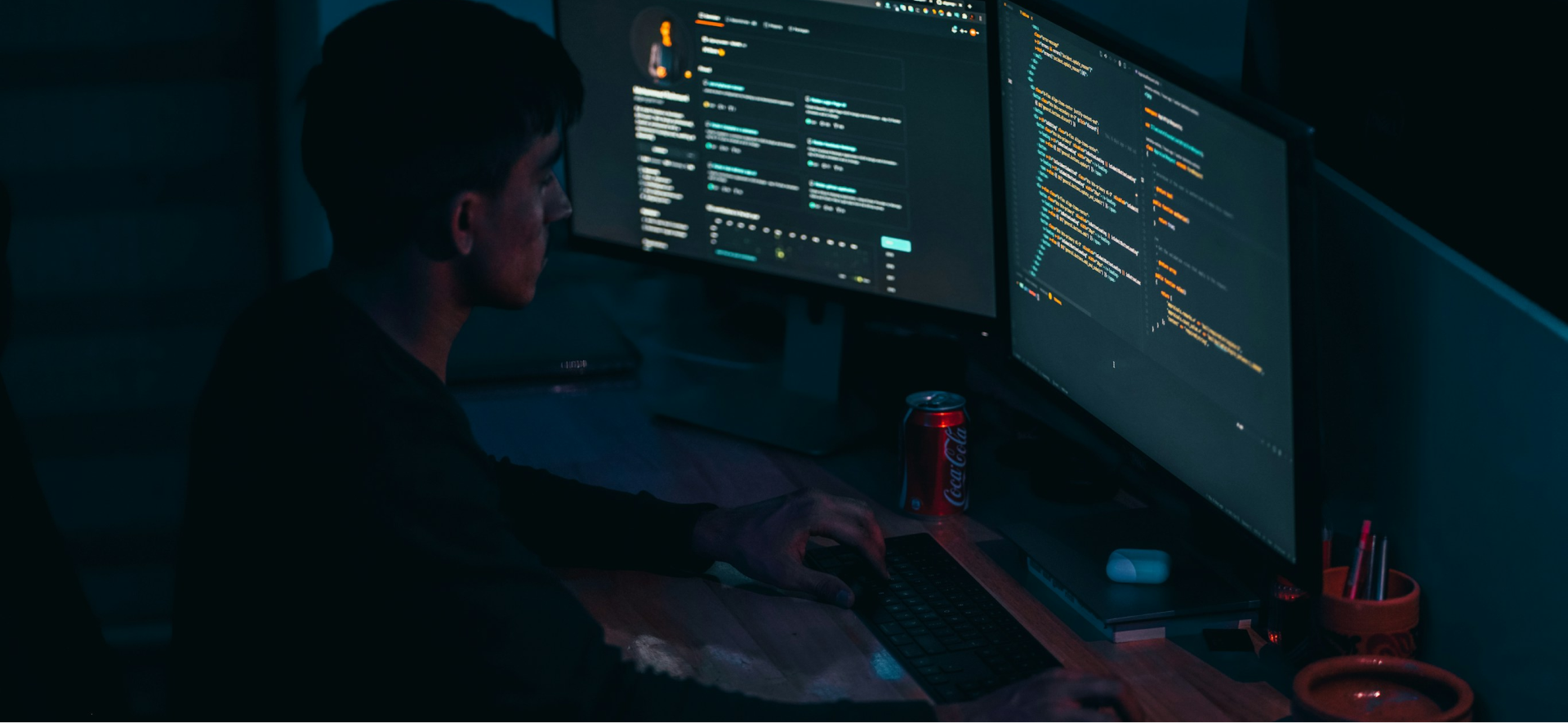 Grayscale image of a developer working at a desk with multiple monitors.