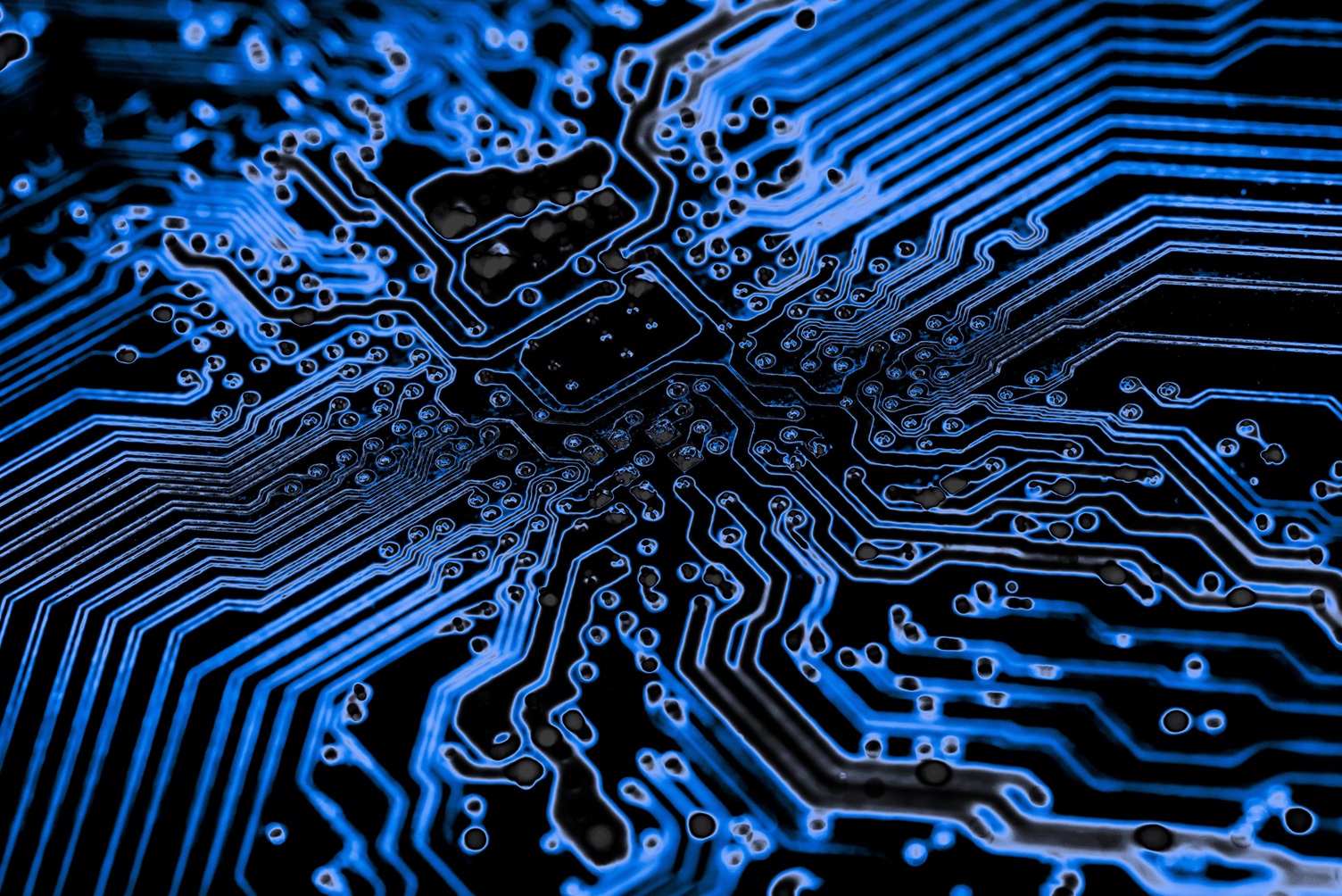 Grayscale close-up of a pair of glasses resting on a laptop keyboard in front of a screen showing code.