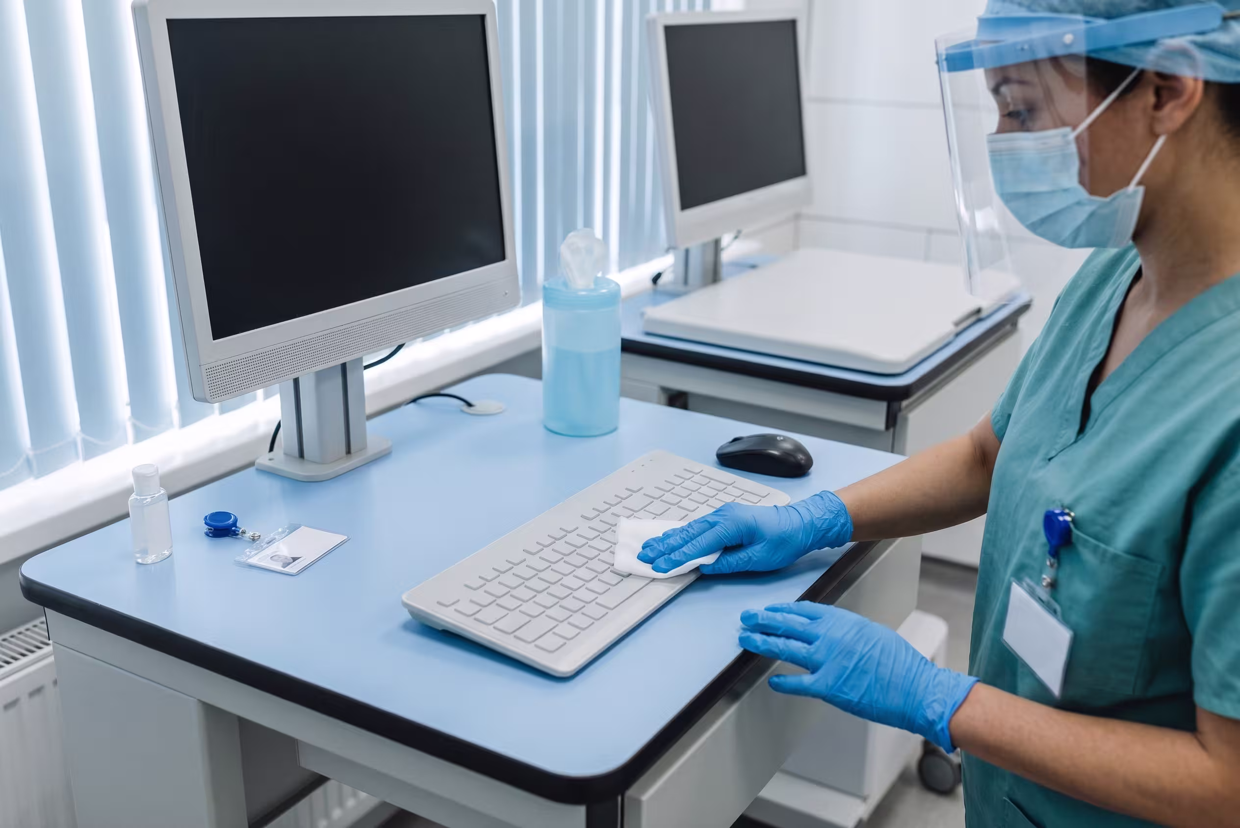 Antimicrobial keyboard and workstation on a hospital ward being wiped down between shifts.