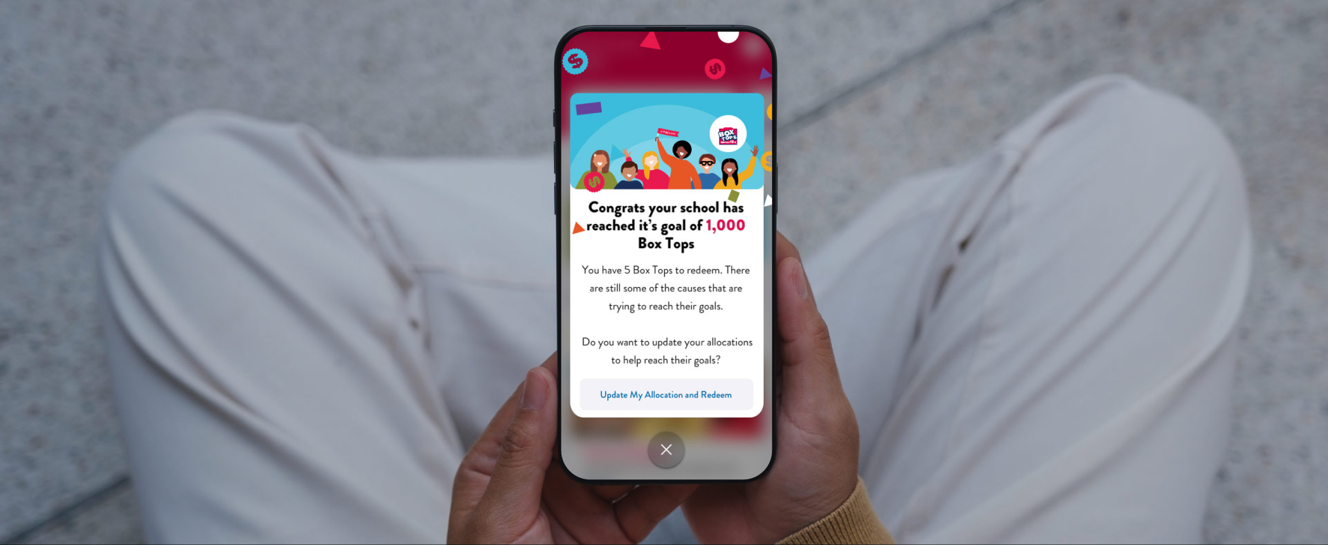 A person looking down at their phone with beyond the box displaying on their screen