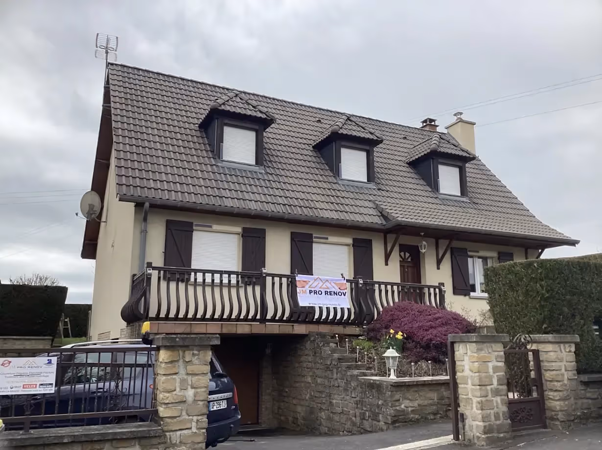 Toit rénové, tuiles béton uniformément rouges, sans traces ni mousse, sous ciel dégagé à Sedan.