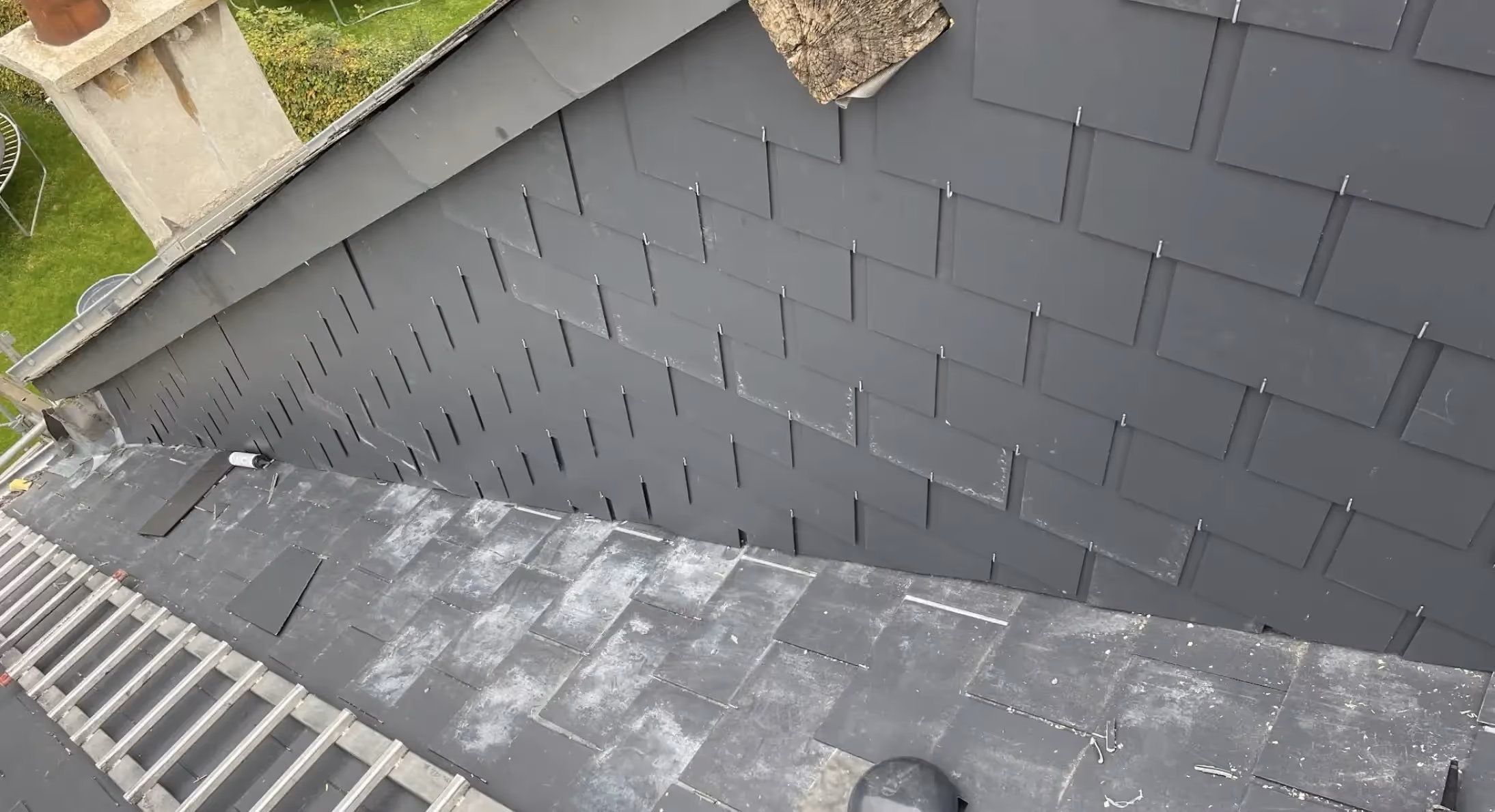 Rive du toit rénovée avec ardoises neuves, couleur uniforme, absence de traces, ciel dégagé à Glaire.