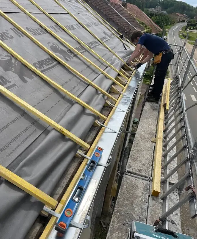 Nouvelles gouttières zinc brillantes bien alignées, bandeaux propres, ciel couvert à Donchery.