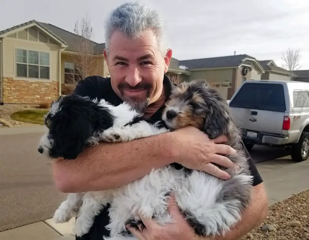 Dale Horton, owner of Denver Dream Builders, holding Huck and Rudy, showcasing his love for dogs and his warm personality