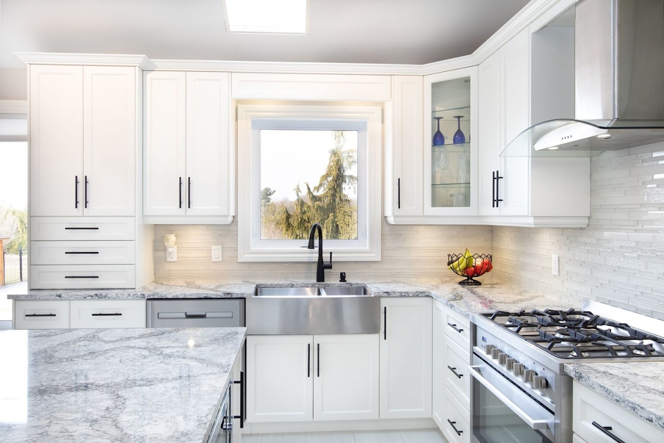 Modern kitchen with white cabinetry, marble countertops, a stainless steel farmhouse sink, and large window, designed and built by Denver Dream Builders.