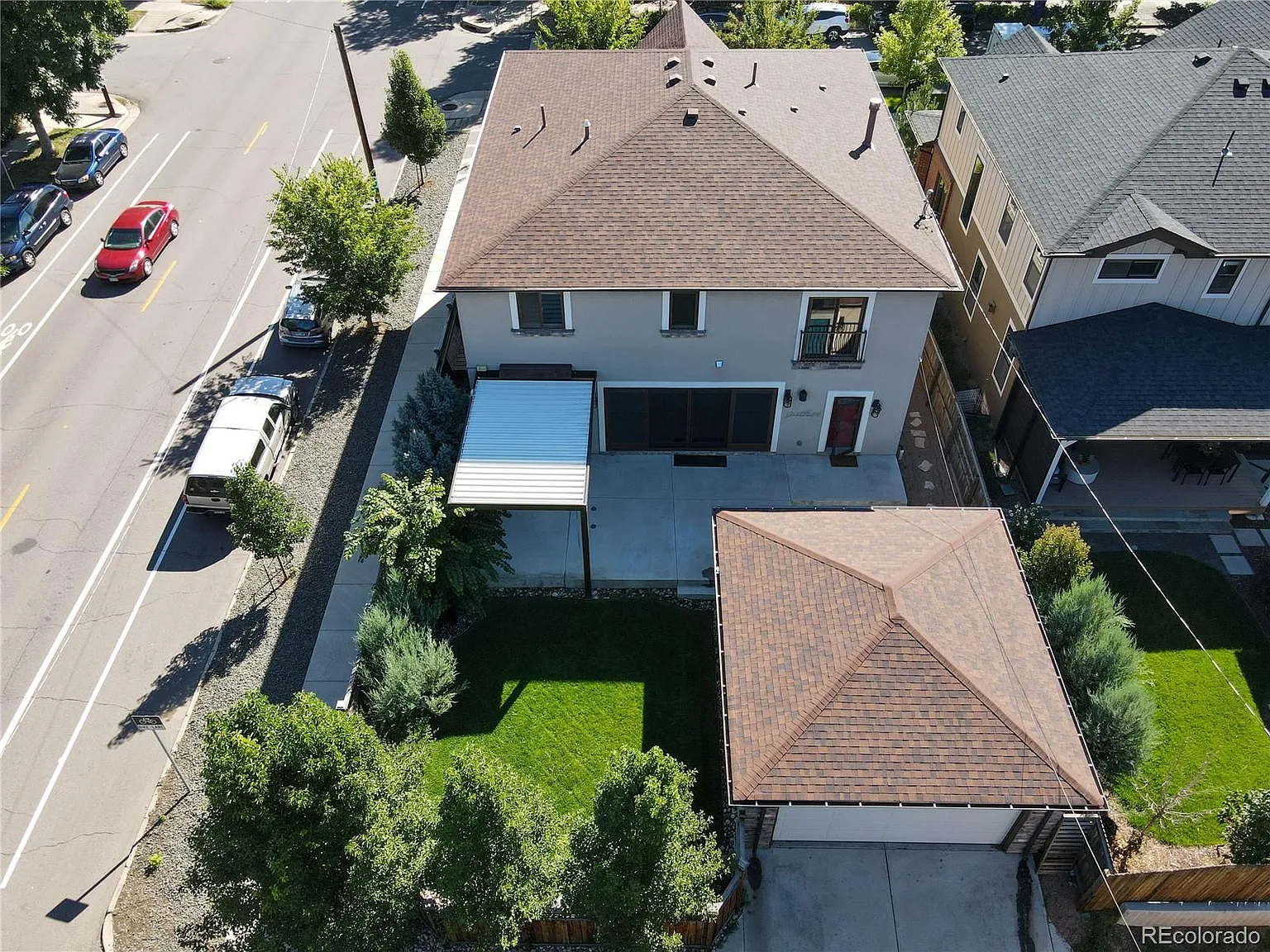 Aerial view of a newly constructed home with a spacious backyard, patio cover, and detached garage, completed by Denver Dream Builders.