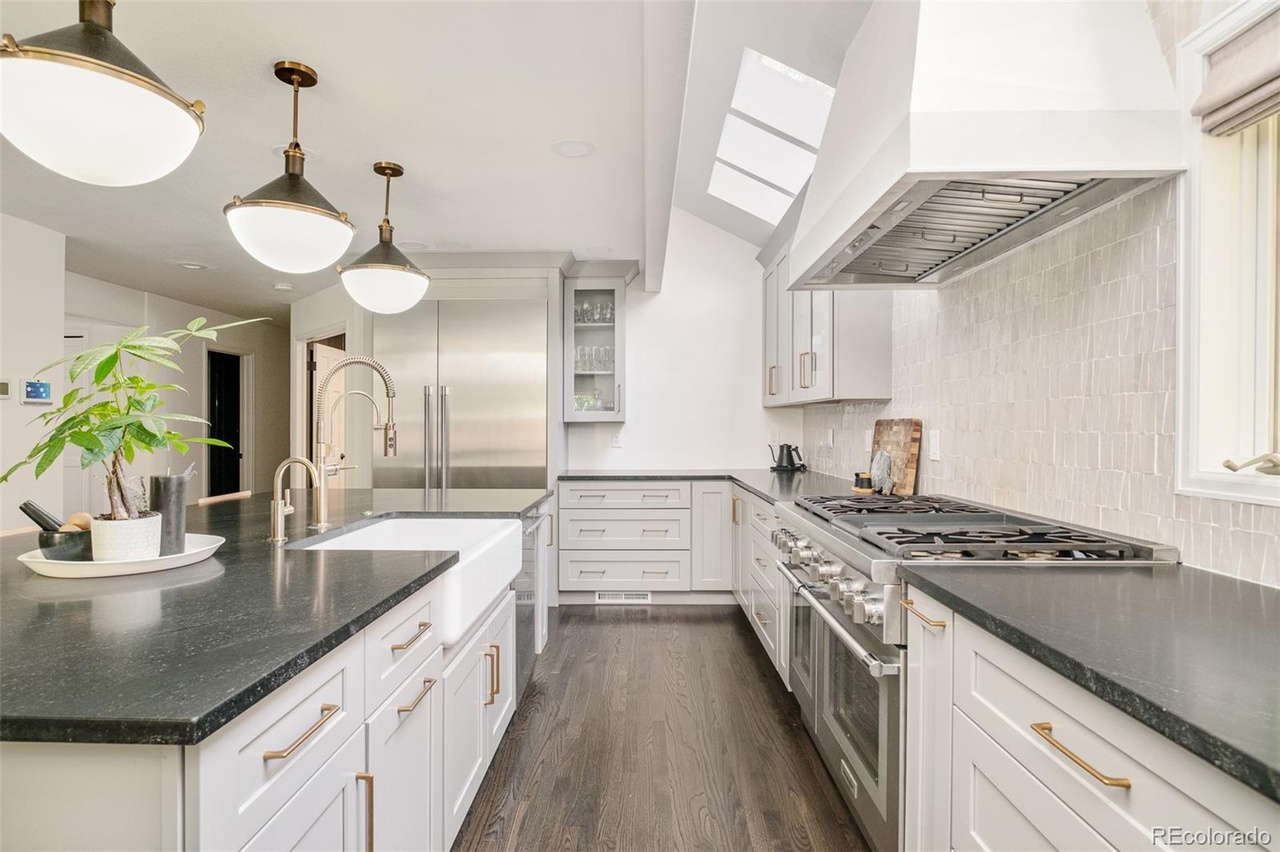 Modern kitchen remodel in Hilltop Denver featuring white cabinetry, dark countertops, and brass fixtures.