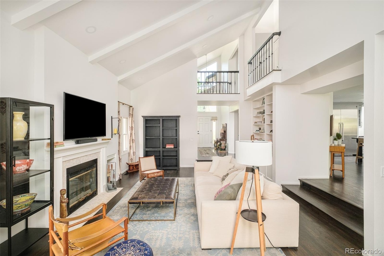 Bright living room in a Hilltop Denver home remodel with vaulted ceilings, fireplace, and open loft railing above.