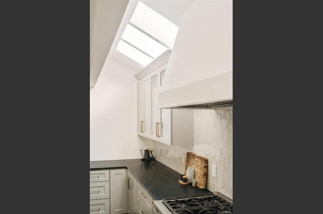 Kitchen corner in a Hilltop Denver remodel with skylights, light cabinetry, and black countertops.