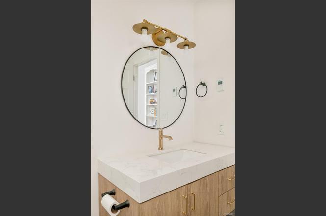 Bathroom vanity remodel with marble countertop, brass fixtures, and round mirror detail.