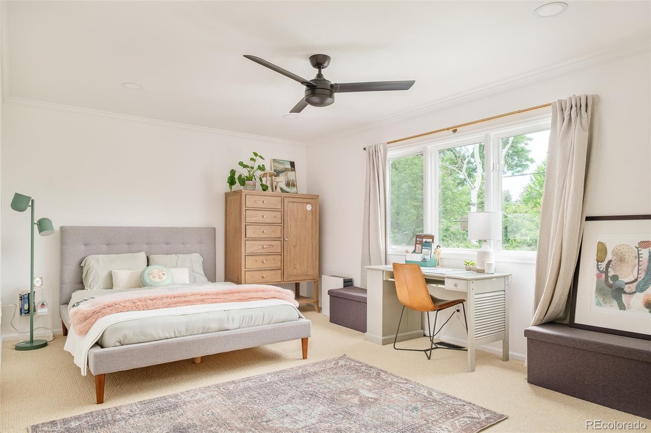Guest bedroom remodel with large windows, workspace nook, and modern ceiling fan.
