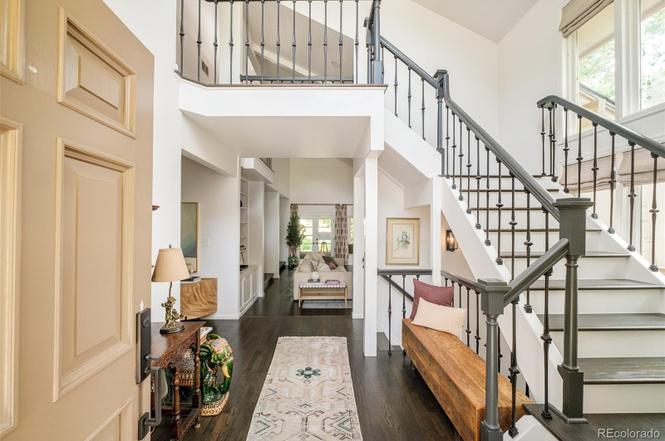 Entryway and staircase of a Hilltop Denver home remodel with wrought iron railings, hardwood floors, and natural light.