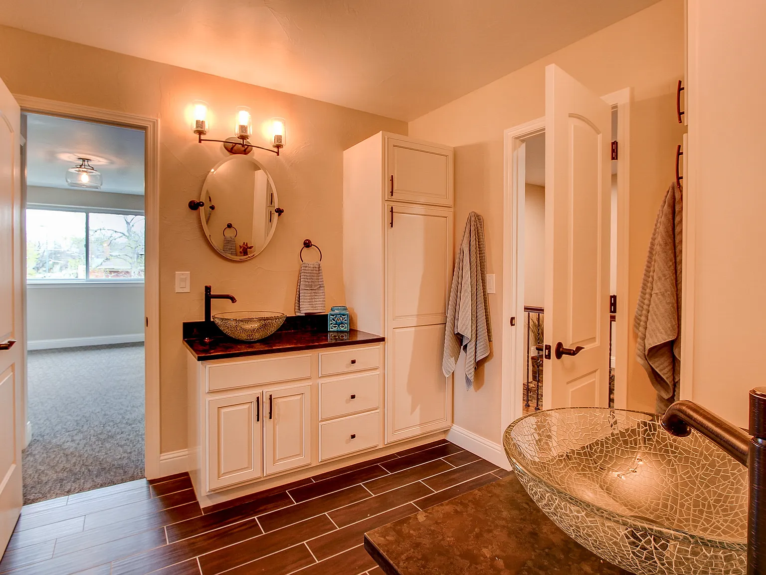 Stylish bathroom with dual vessel sinks, round mirror, and walk-in shower featuring slate flooring