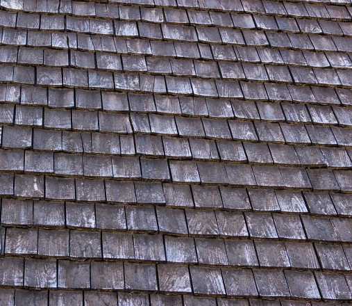 Curling and splitting cedar shake roof with felt underlayment exposed where shakes are missing