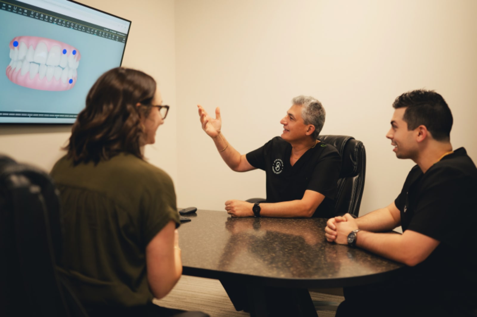 Team members discussing treatment plan at consultation table with dental model