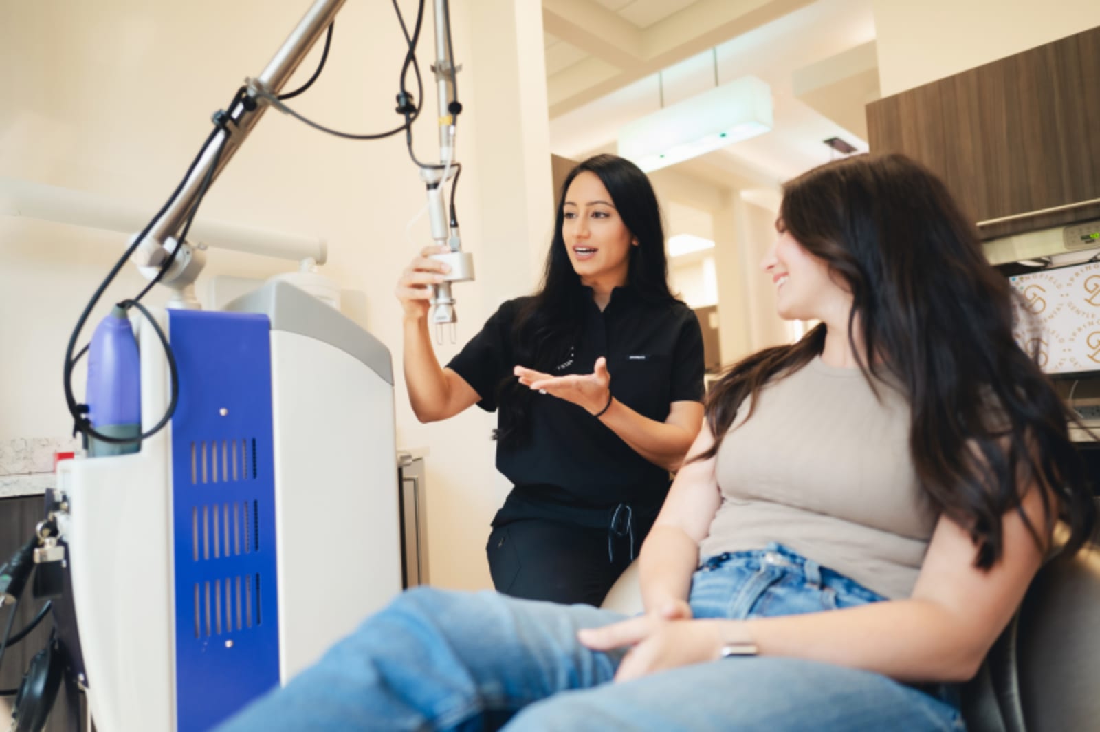 Dentist explaining procedure to patient in treatment room with equipment visible