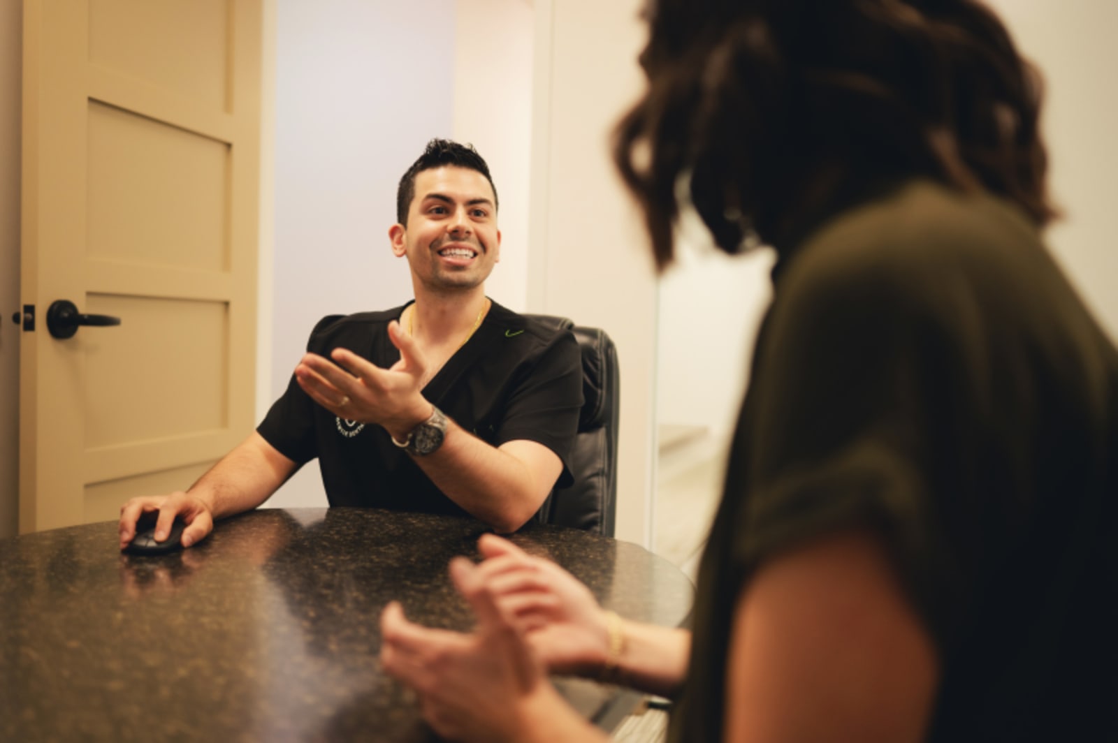 Dentist consulting with patient at desk during treatment planning discussion