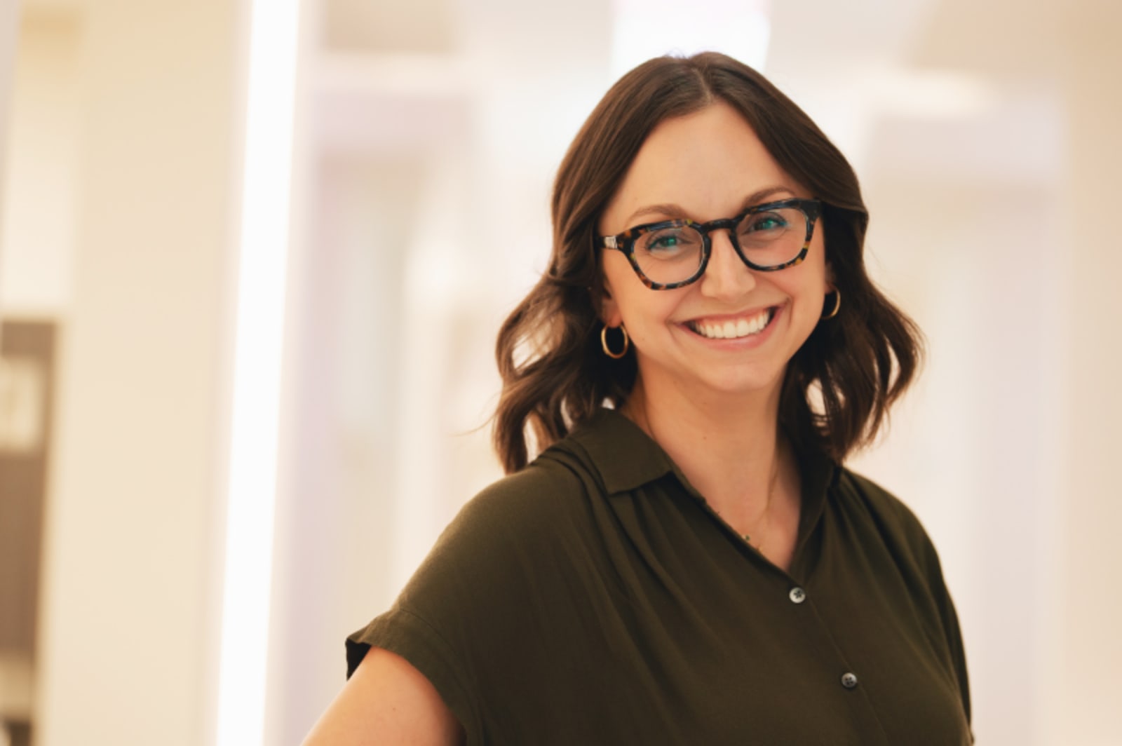 Female dental team member smiling at camera wearing branded dental practice apparel