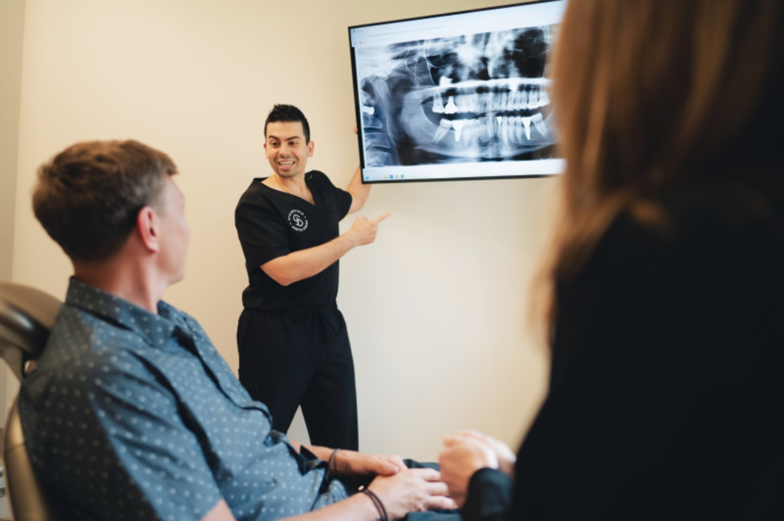Dentist presenting X-ray images on monitor to patient during consultation