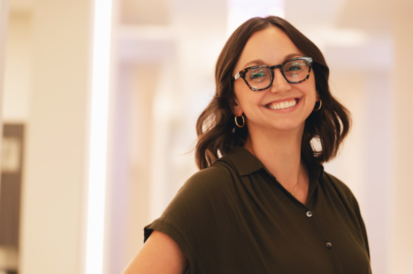 Female dental professional in clinical setting smiling at camera