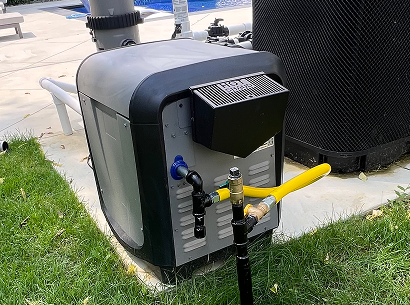 Gas line and fittings connected to outdoor pool heater beside backyard pool equipment.