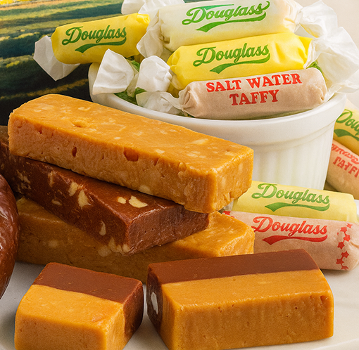 Various pieces of salt water taffy candy, some wrapped in Douglass branded yellow and white wrappers, and several unwrapped in different flavors.