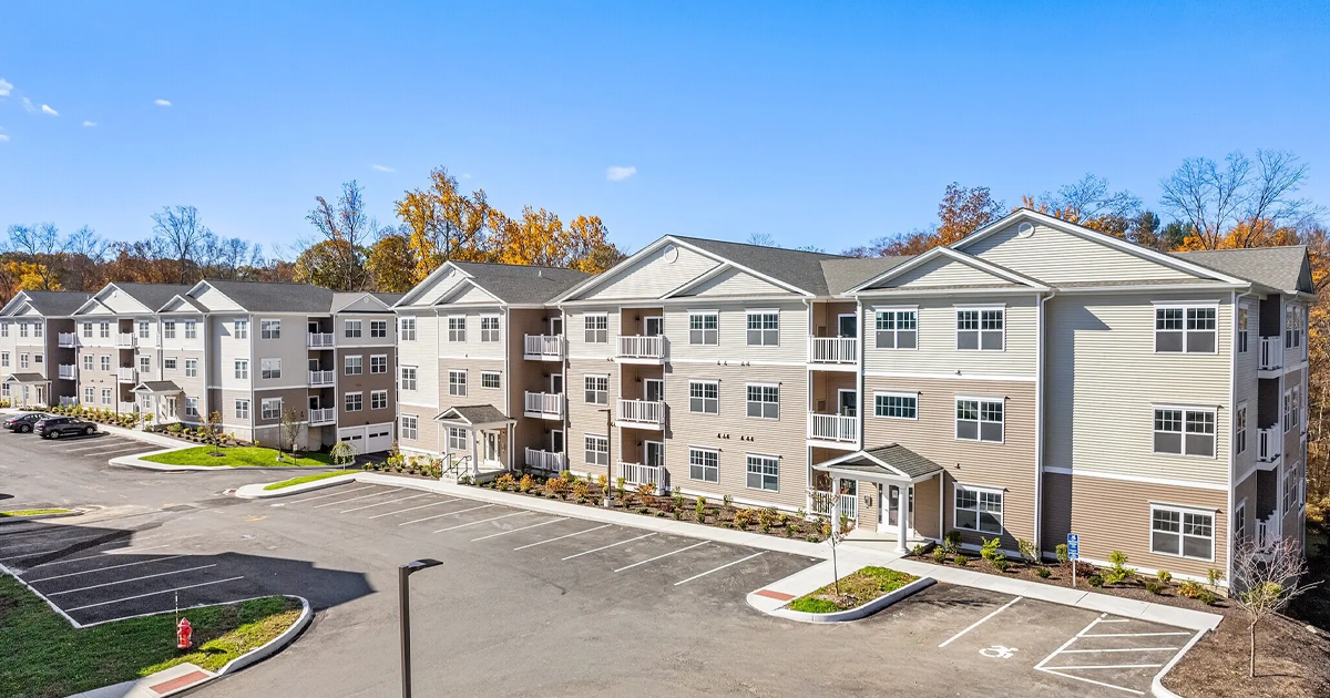 Exterior view of the luxury Covered Bridge apartments in Newtown, CT, with green surroundings and spacious parking