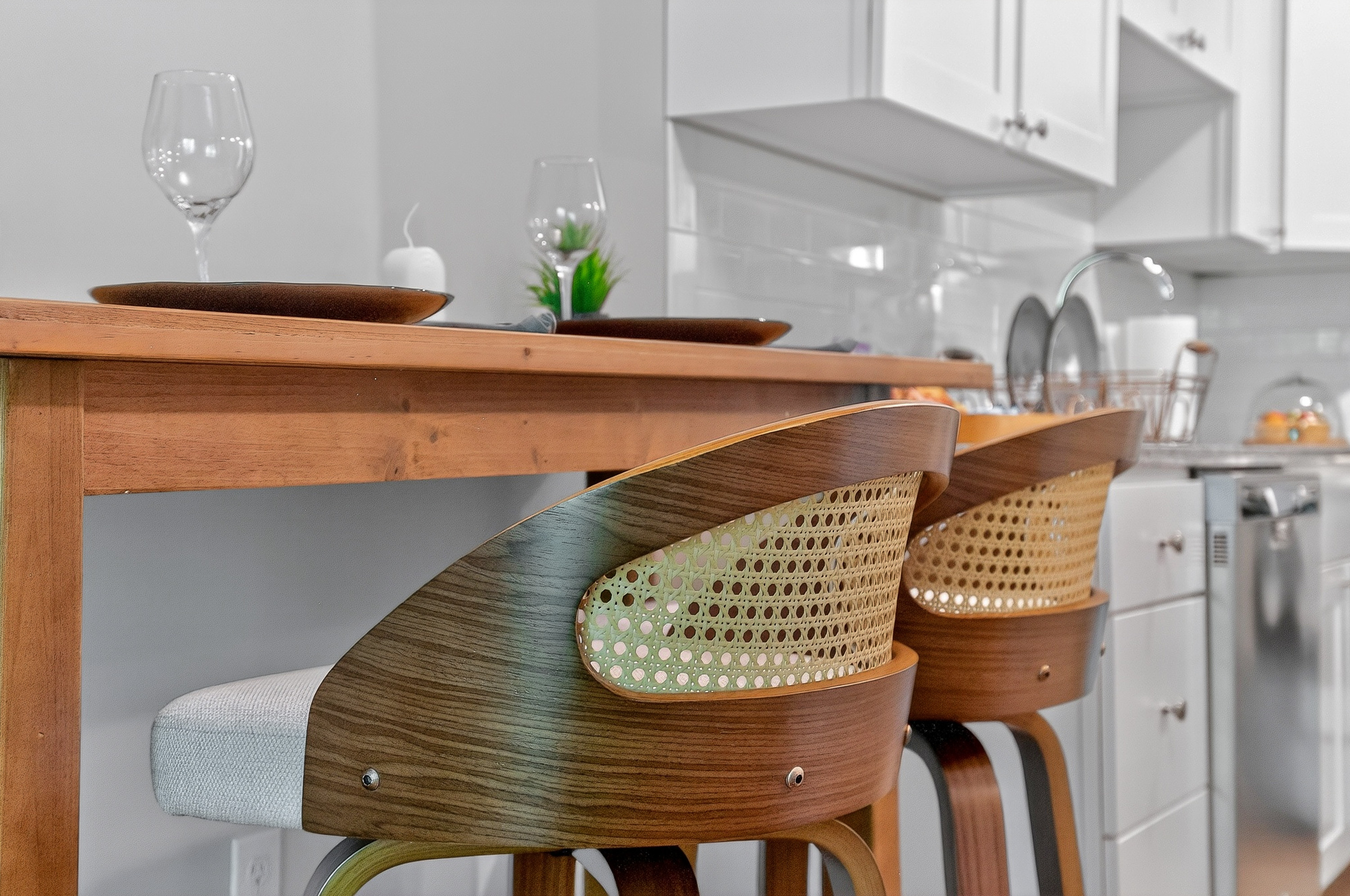 Wood and cane modern bar stools at a wooden counter in a white kitchen setting.