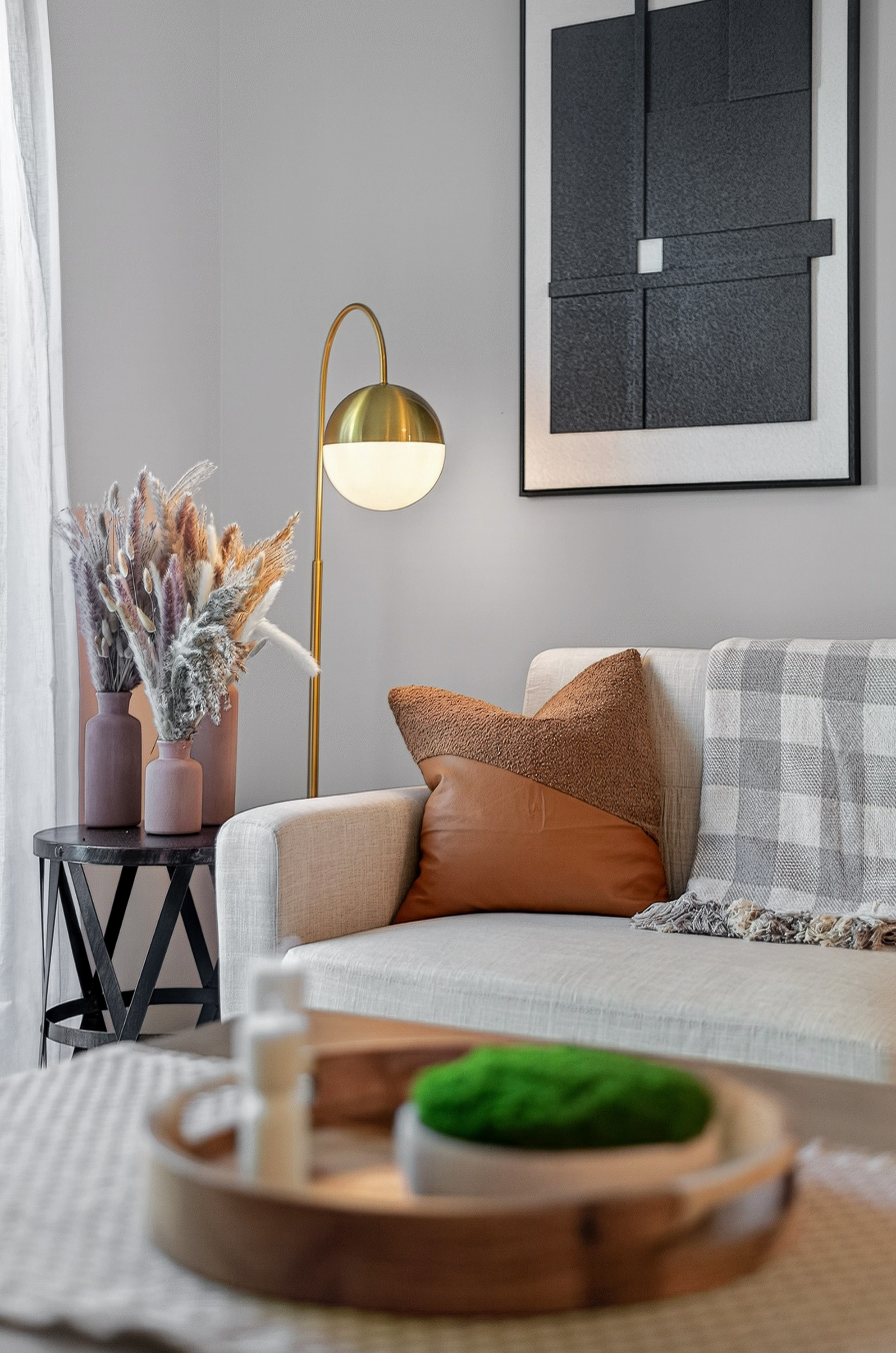 Modern living room featuring a beige sofa with a leather and fabric pillow, floor lamp, and side table.