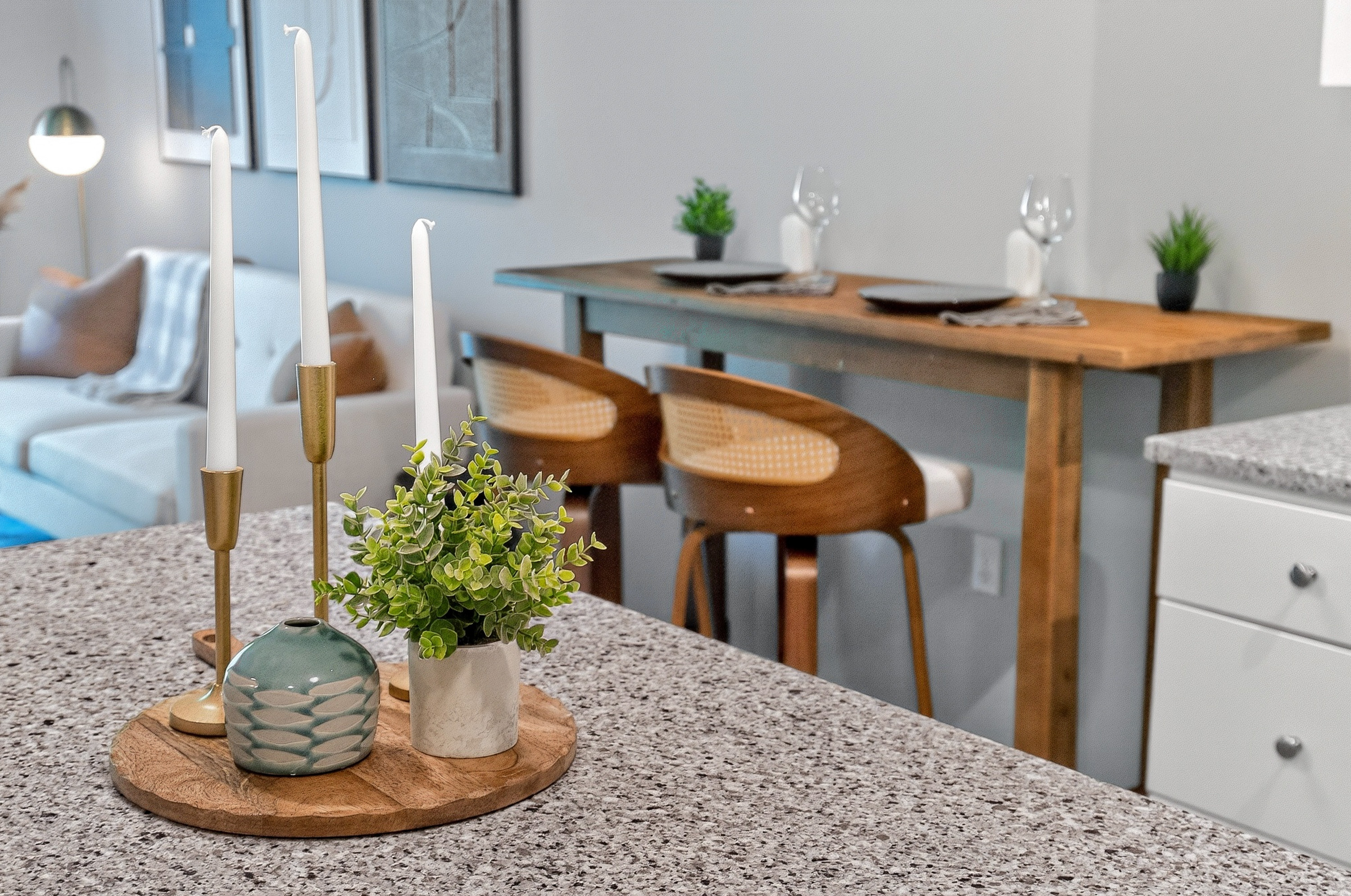 Covered Bridge Kitchen island with wooden tray holding three white candles and two small potted plants.