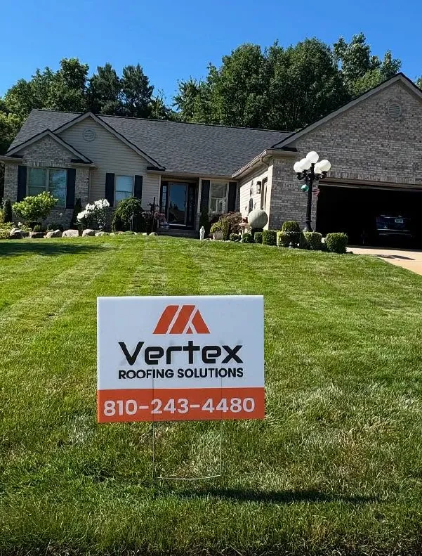 Well-maintained lawn with a Vertex Roofing Solutions sign displaying a phone number in front of a one-story brick and siding house with a dark roof.