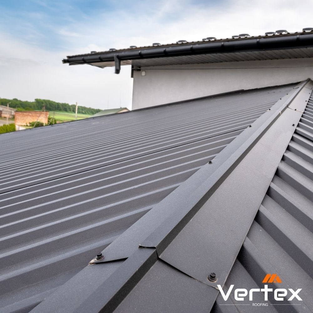 Close-up of a modern gray metal roofing with ridges under a partly cloudy sky.