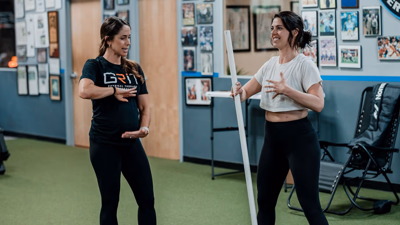 Physical therapist and patient in athletic wear discussing exercise technique in a Richmond, VA physical therapy clinic.