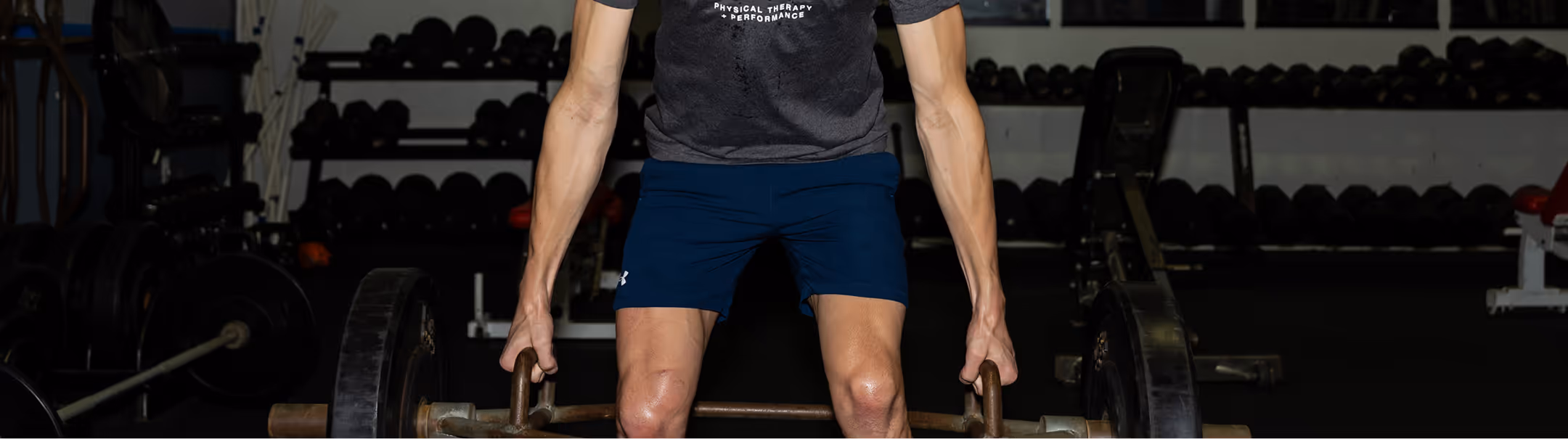 Athlete lifting a barbell with weights in a Richmond, VA physical therapy clinic.